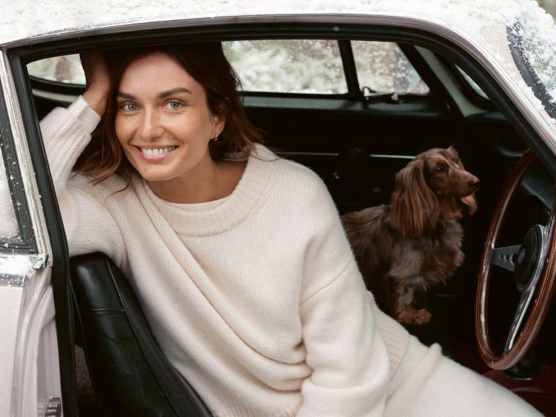 a woman sitting in a car with a dog in the back seat