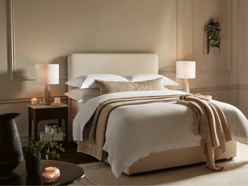 a woman sleeping in a bed with white sheets and pillows