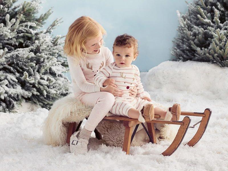 a little girl sitting on a sled with a baby boy