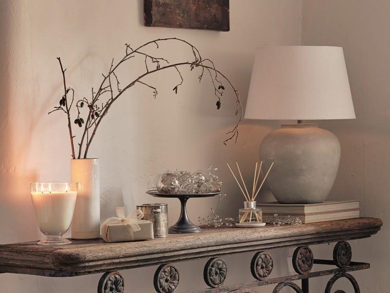 a fireplace mantel with a lamp, candles, and a vase