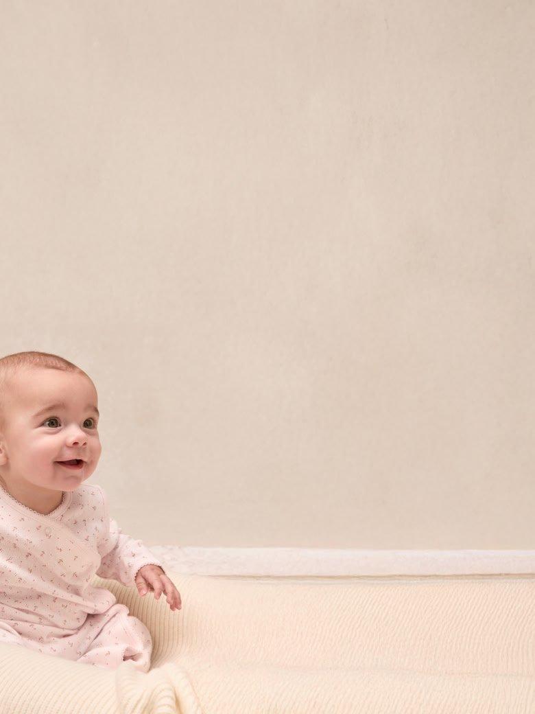 a baby sitting on a white couch smiling at the camera
