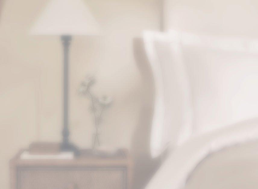 a blurry picture of a bed with a night stand and a lamp