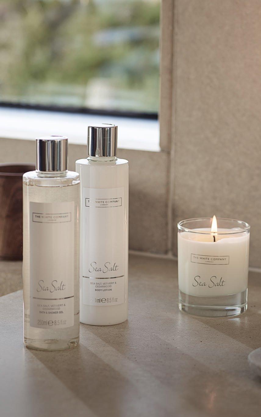 a couple of bottles of lotion sit on a counter next to a candle