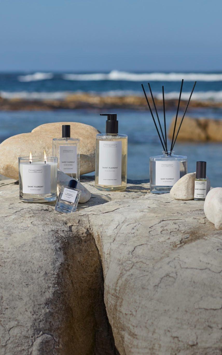 a group of bottles of perfume sit on a rock by the ocean