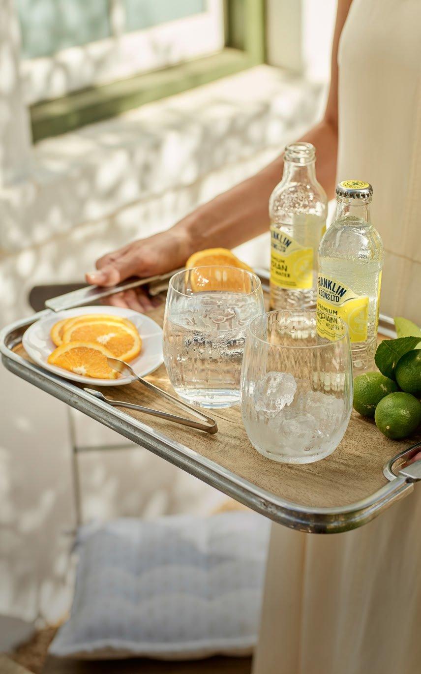 a person holding a tray with drinks and glasses of water