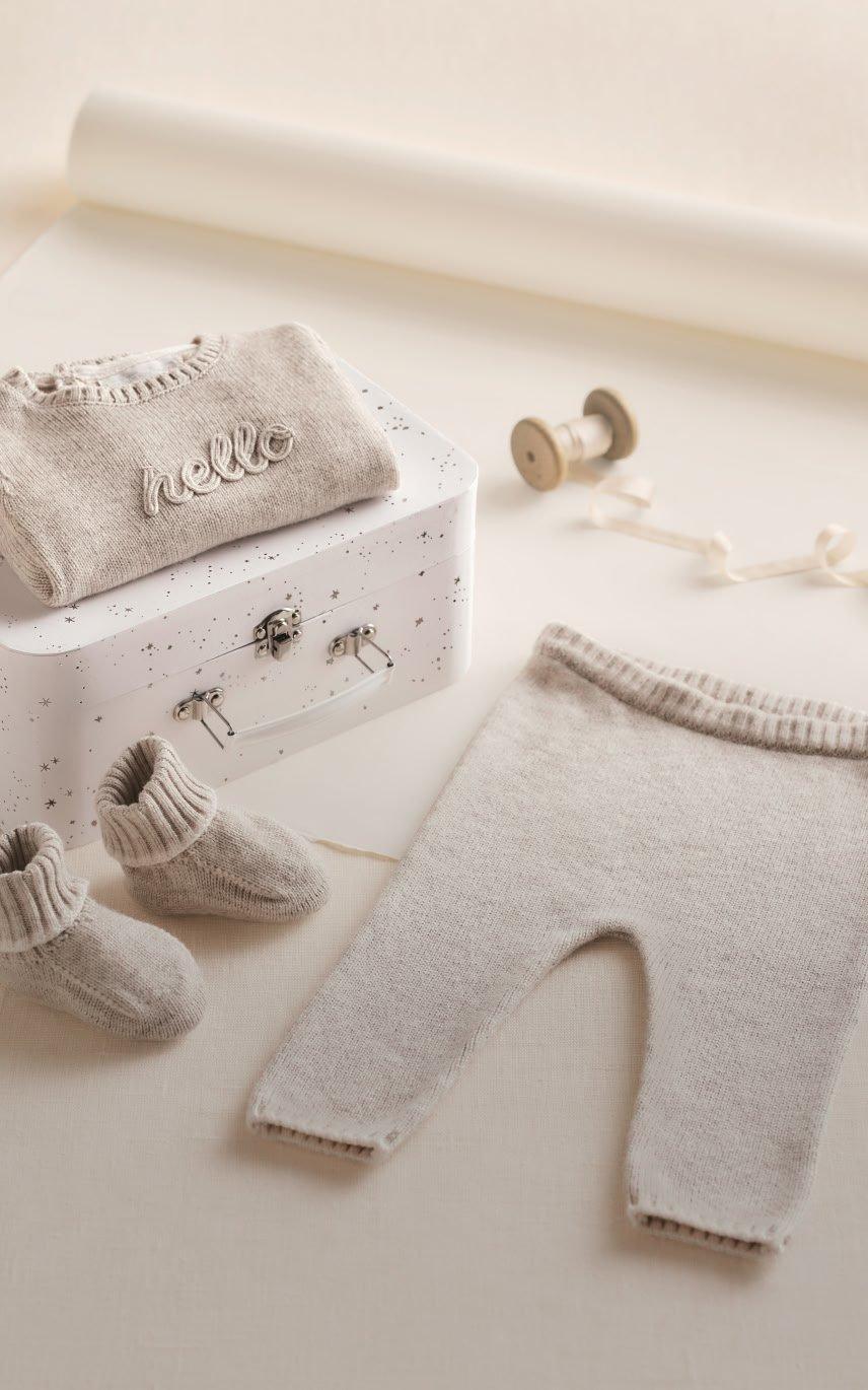 a baby's clothes are laid out on a table next to a suitcase