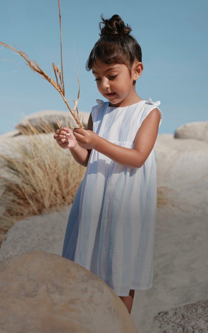 a little girl standing on a rock holding a plant
