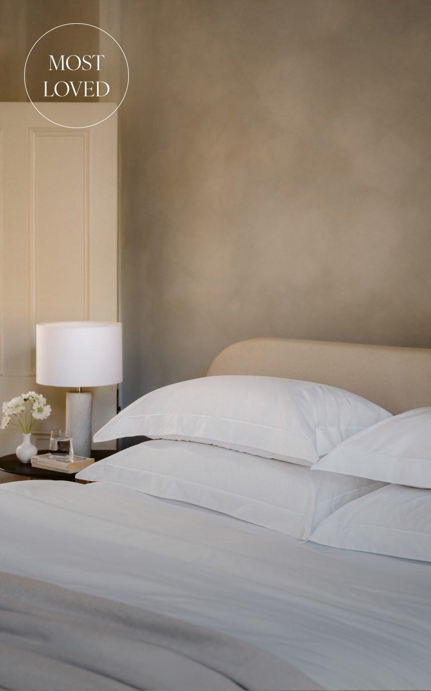a bed with a white comforter and pillows on it