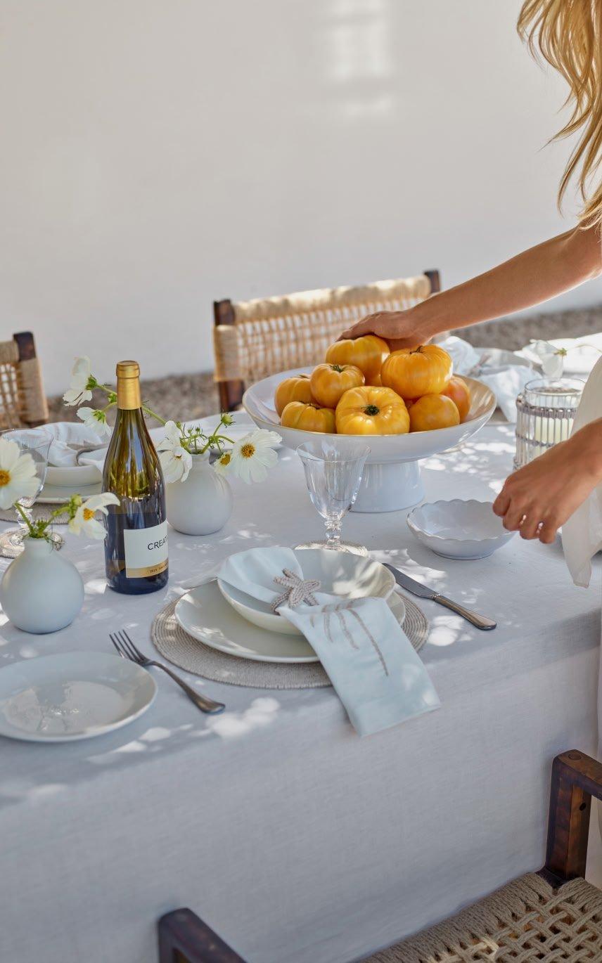 a woman holding a bowl of oranges on a table