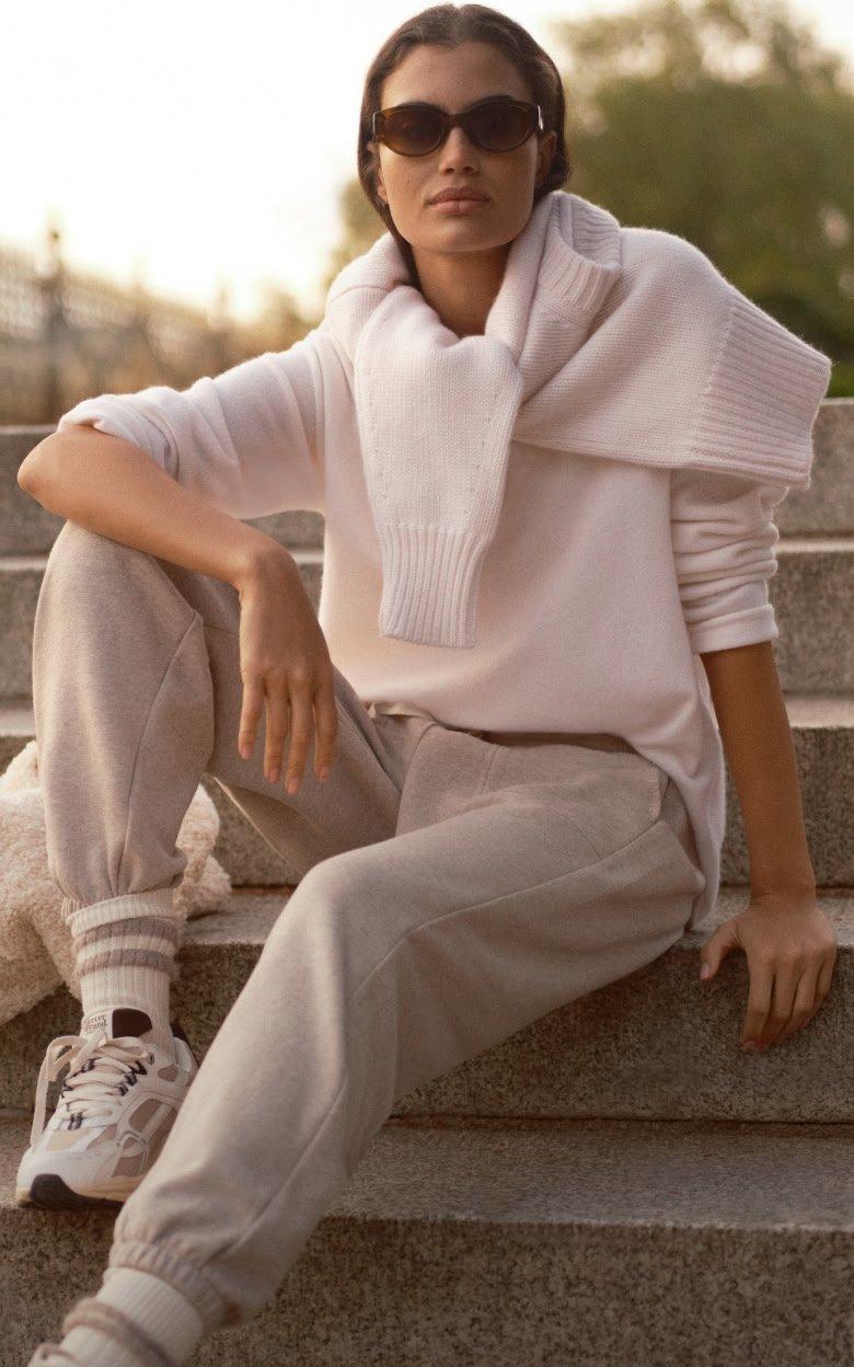 a woman in a white sweater and white pants standing up