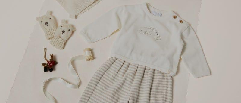 a baby's outfit laid out on a table with a hat and gloves