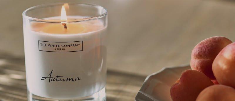 a plate of peaches sitting next to a candle on a table