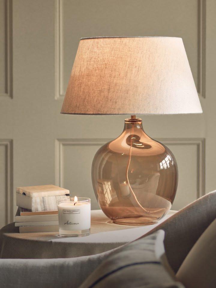 a table with a lamp and a candle on it next to a book