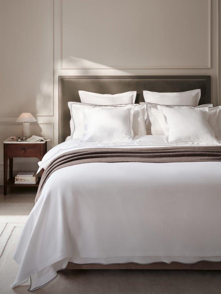 a bed with white sheets and pillows in a bedroom