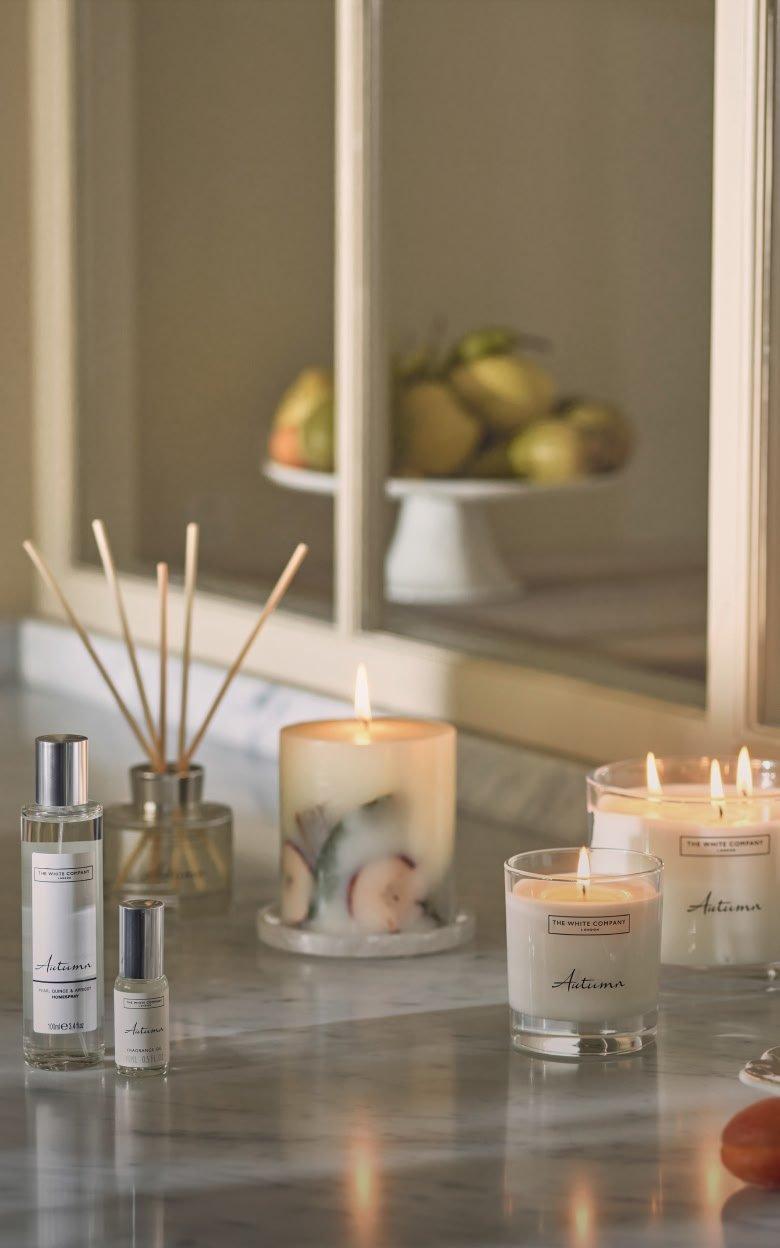 a counter with candles, a vase of flowers and a mirror