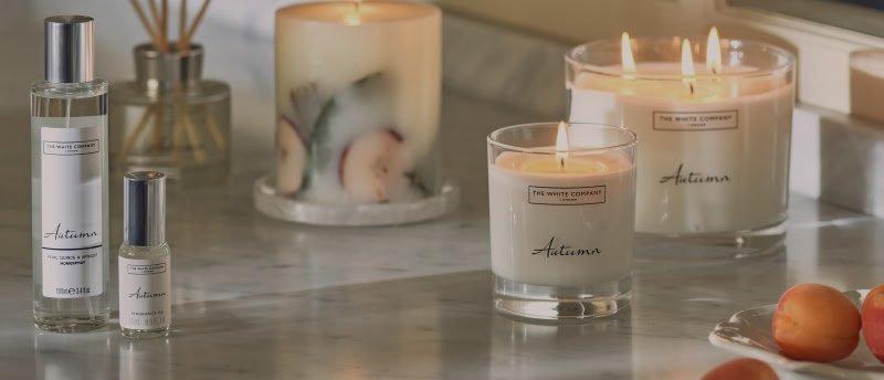 a counter with candles, a bottle of perfume and a glass of water