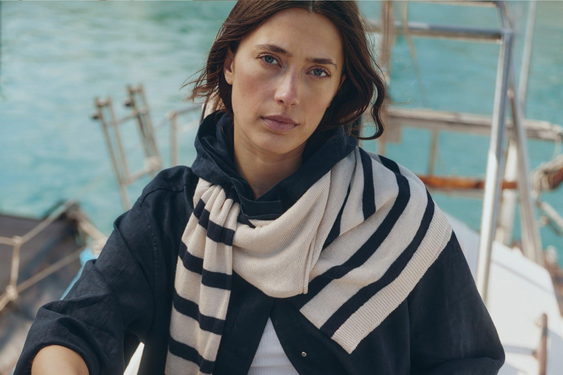 a woman sitting on a boat with a scarf on her neck