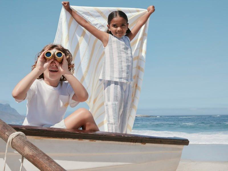 two children on a boat looking through binoculars at a towel