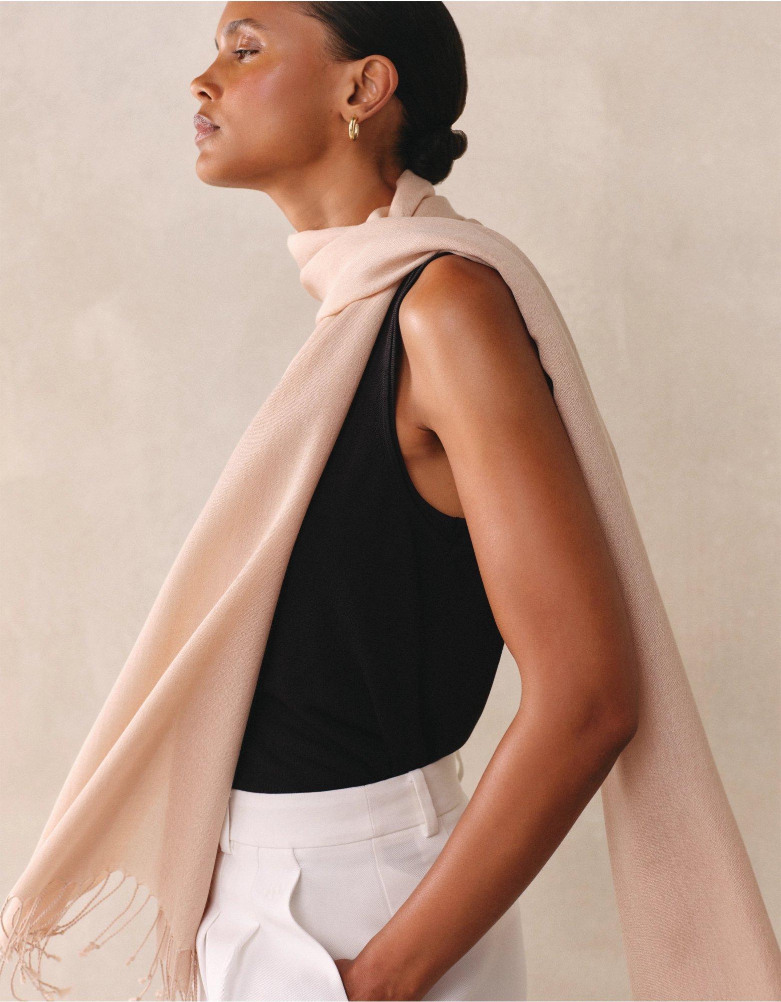 a woman in a white tank top and black pants with a scarf