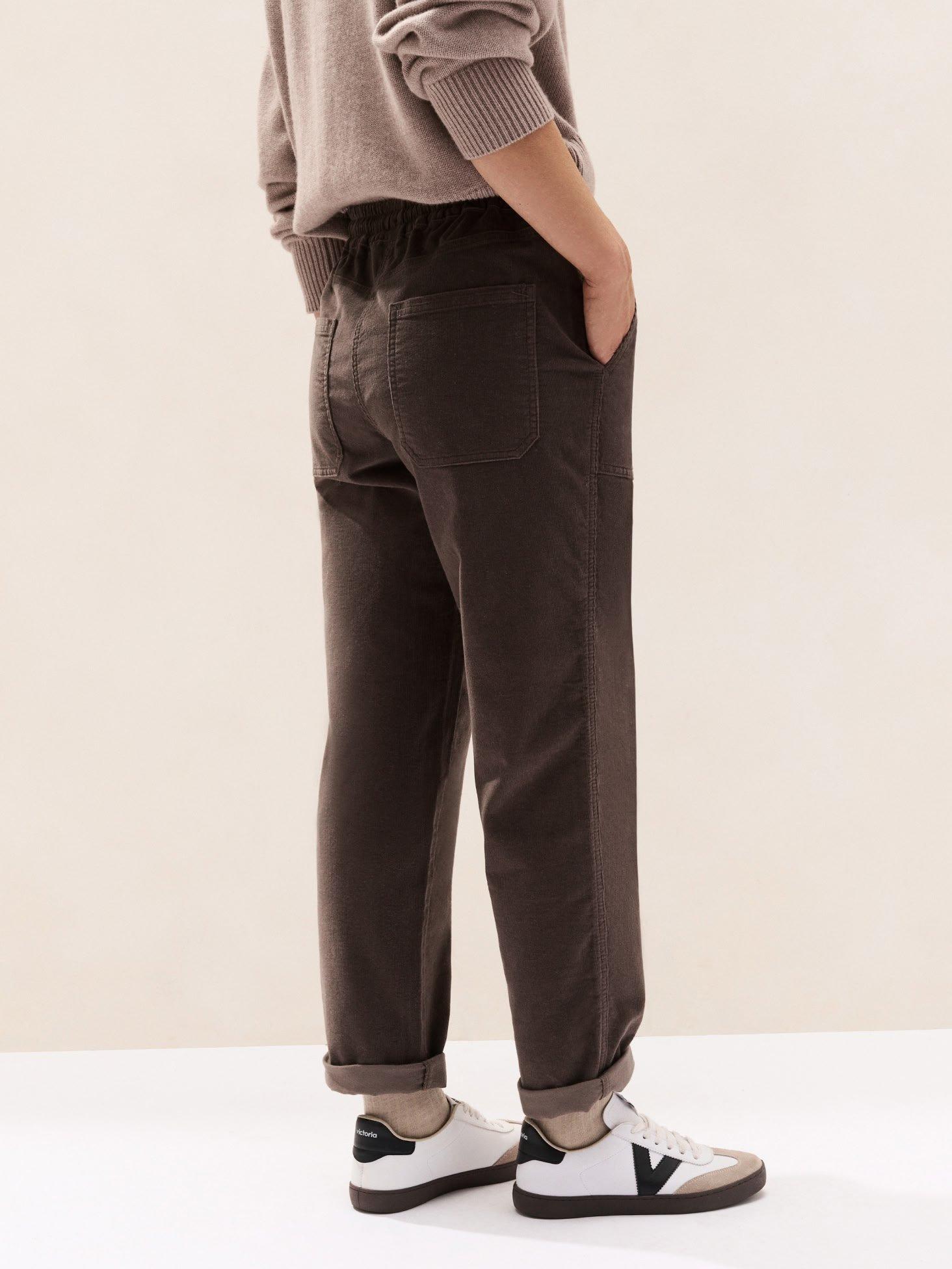 a man in a white shirt and brown pants standing
