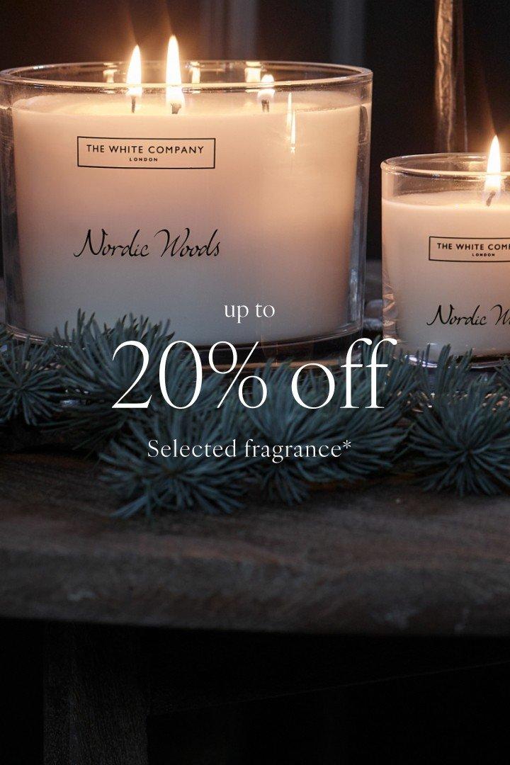 two candles are sitting on a table with a sign that reads 20 % off selected fragrances