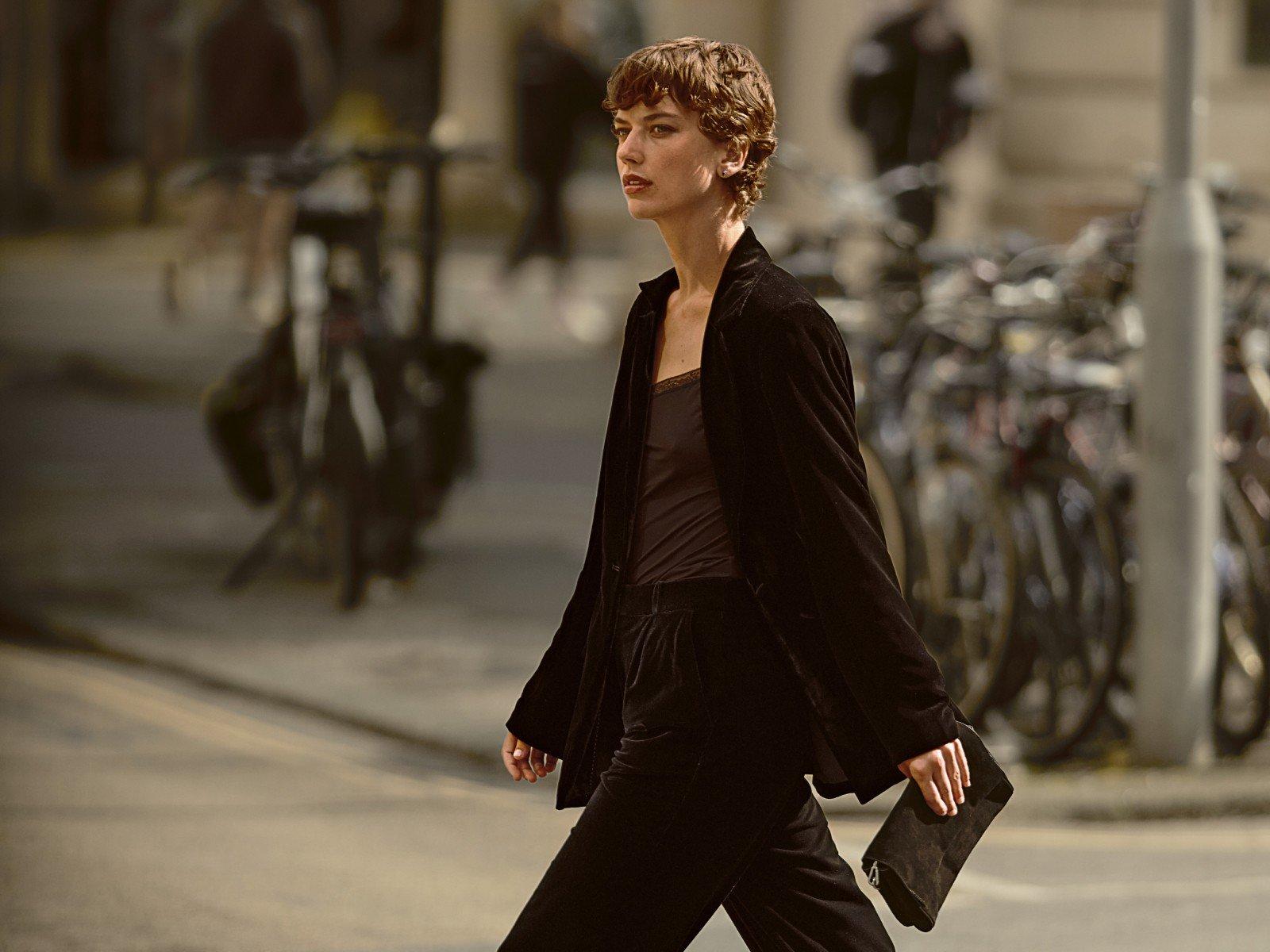 a woman walking down the street with a black purse