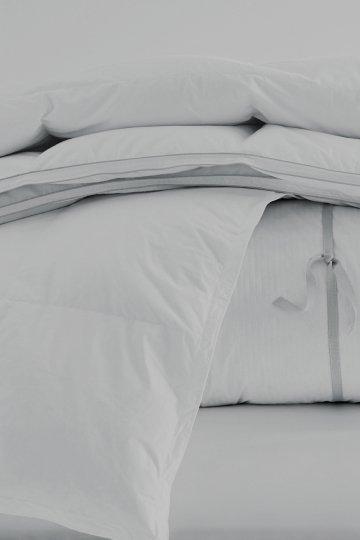 a white bed with a white comforter and pillows on it