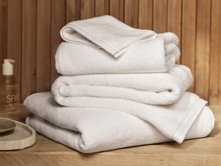 a stack of white towels on a wooden table next to a soap dispenser