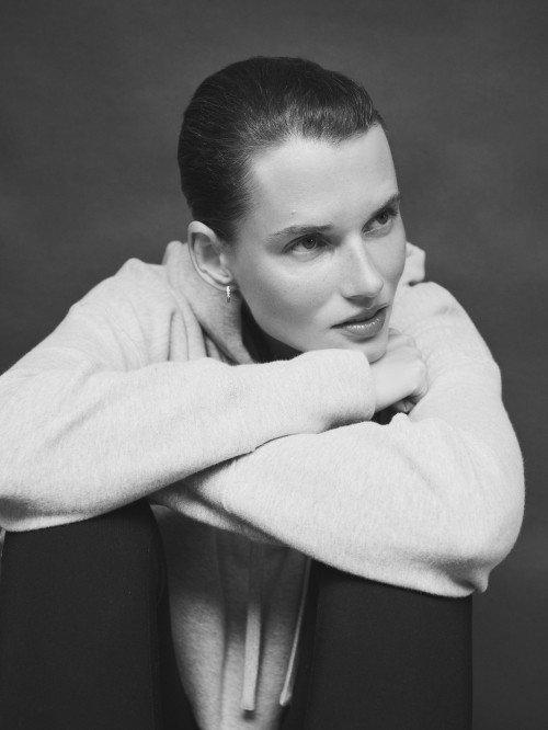 a woman sitting on a bench with her hands on her knees