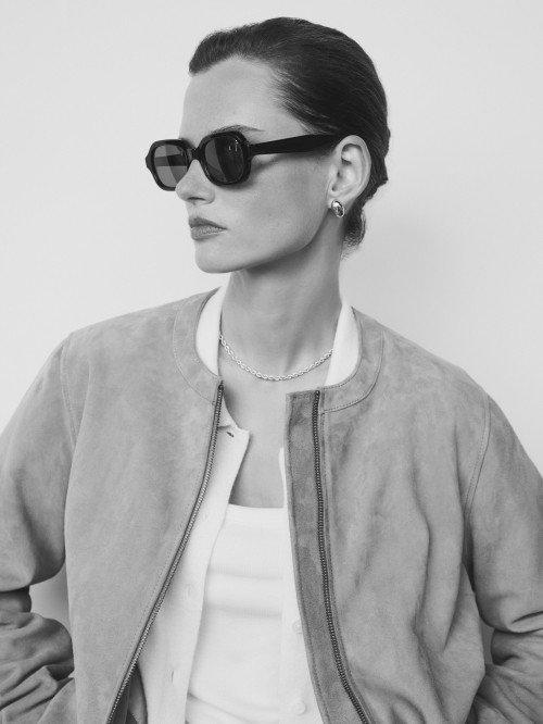 a woman in sunglasses and a jacket posing for a photo