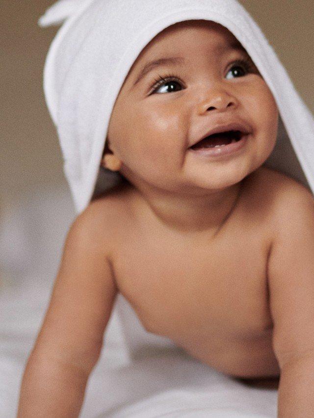 a baby laying on a bed with a towel on his head