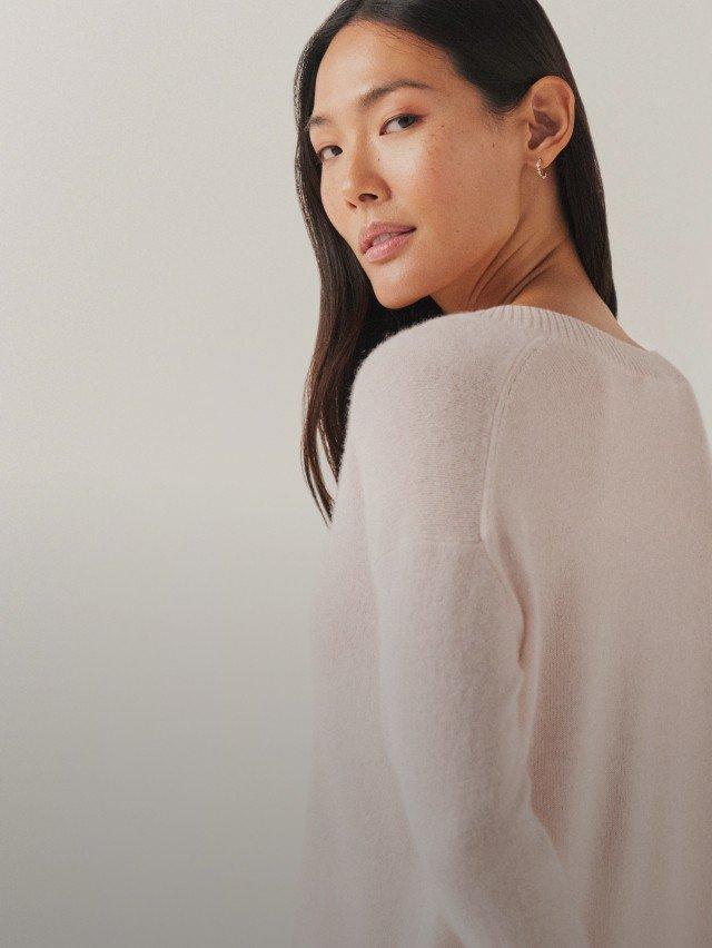 a woman in a white sweater is looking at the camera