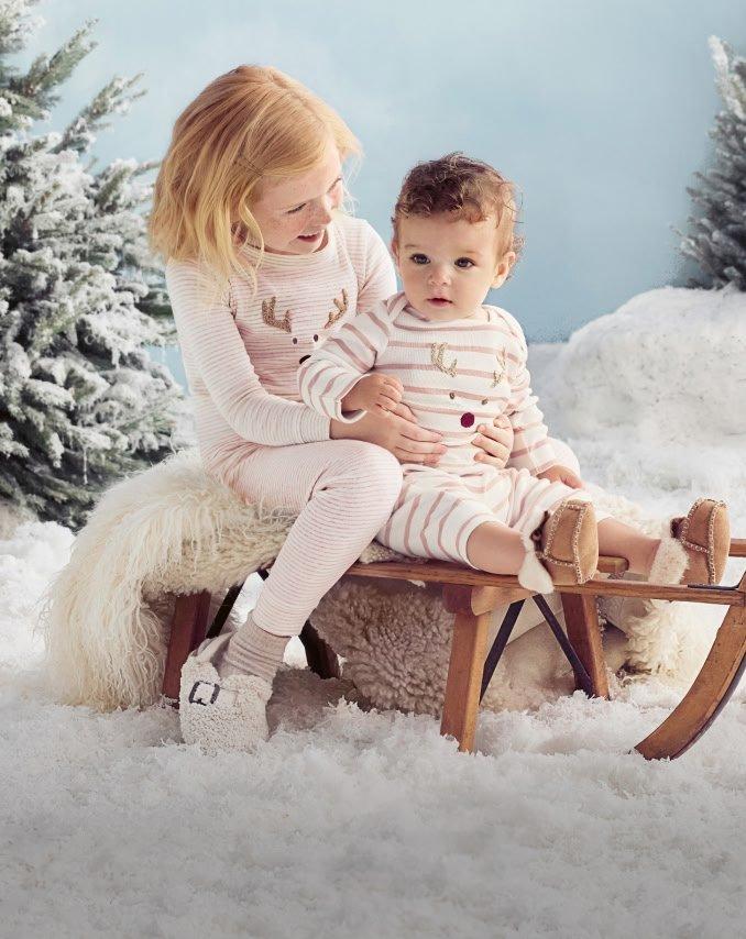 a little girl sitting on a sled with a little boy