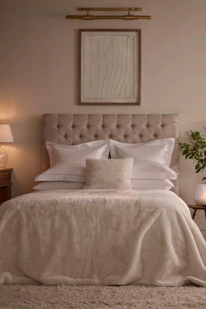 a bed with white sheets and pillows in a bedroom