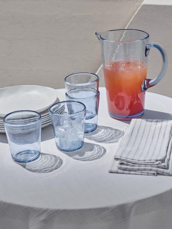 a table with a pitcher and glasses on it with a plate