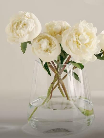a clear vase with white flowers in it on a table