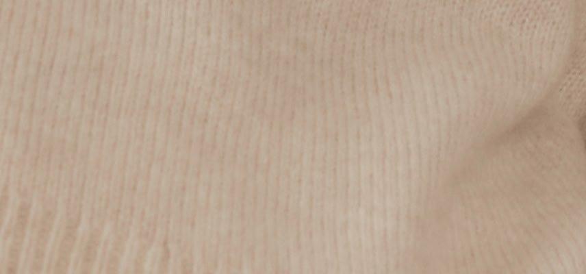 a close up of a button on a sweater with a tan background