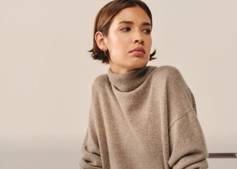 a woman in a turtle neck sweater sitting on a chair