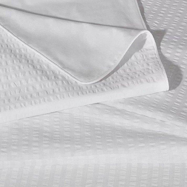 a close up of a white sheet folded up on a bed