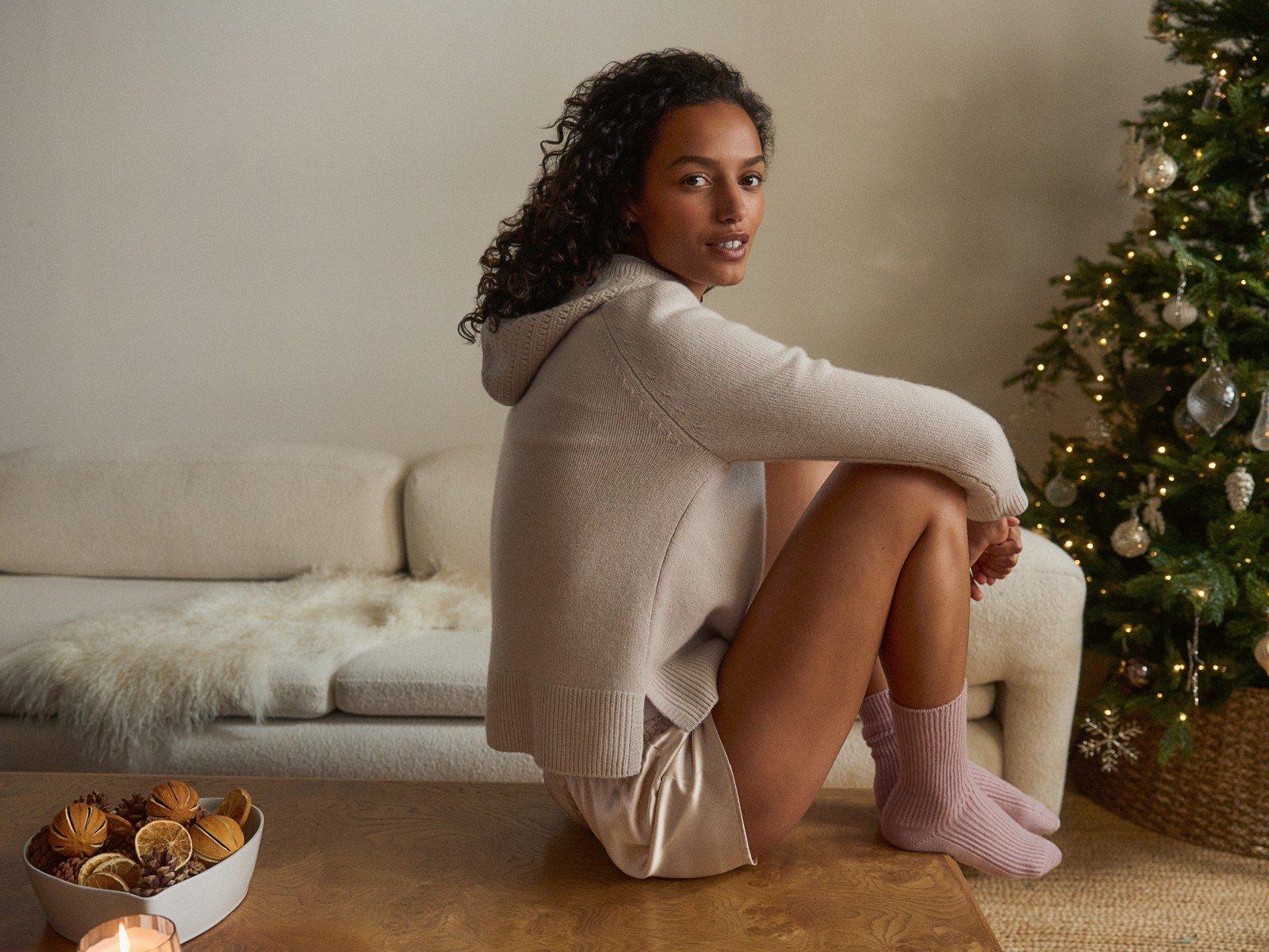 a woman sitting on a table in front of a christmas tree