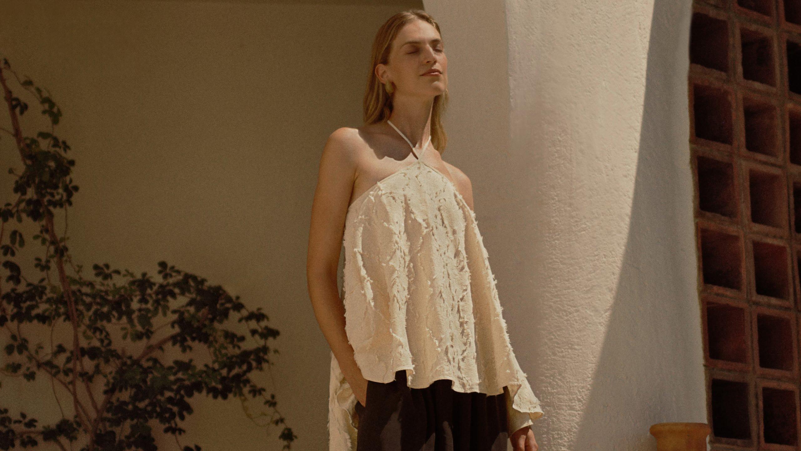 a woman in a white top and black pants standing on a balcony