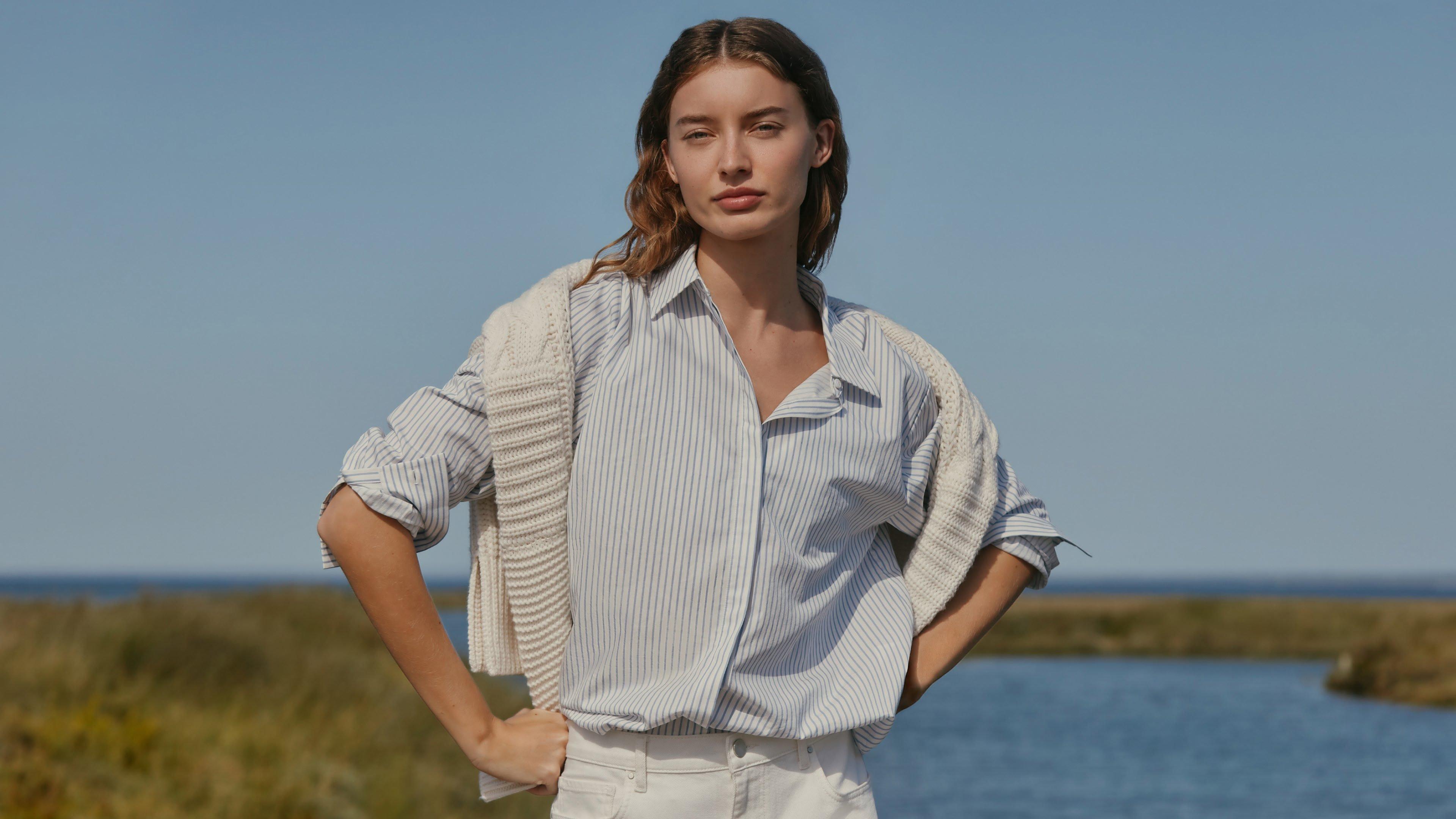 a woman in a white sweater sitting on a couch reading a book