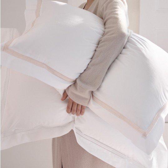 a person holding a pillow in their hands with a white sheet