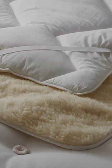 a close up of a white bed with a blanket on it