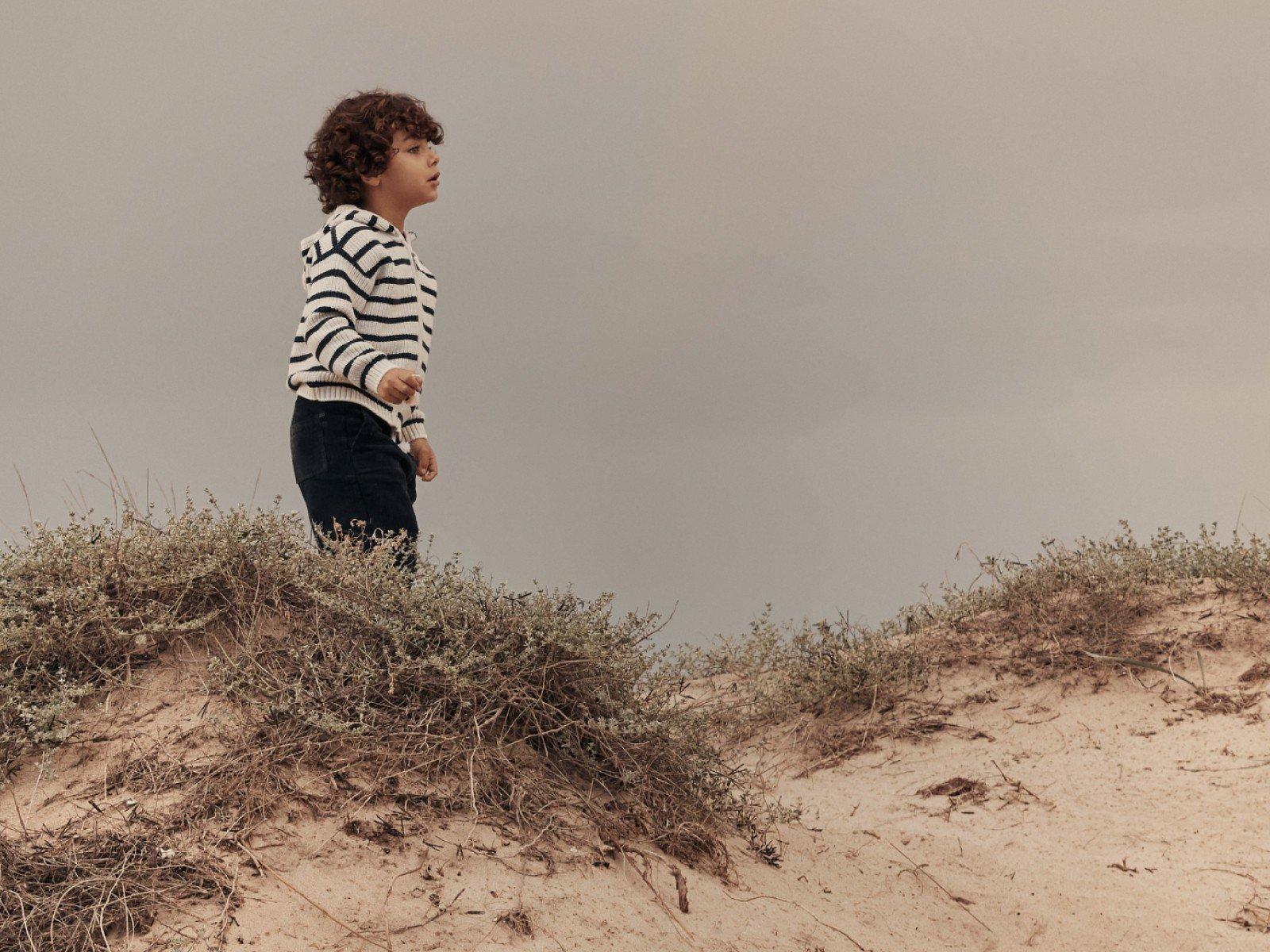 a young boy standing on top of a hill with a kite