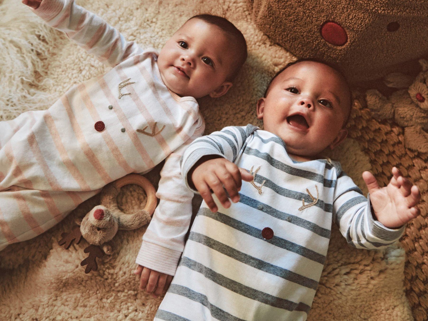 two babies laying on a bed with a stuffed animal