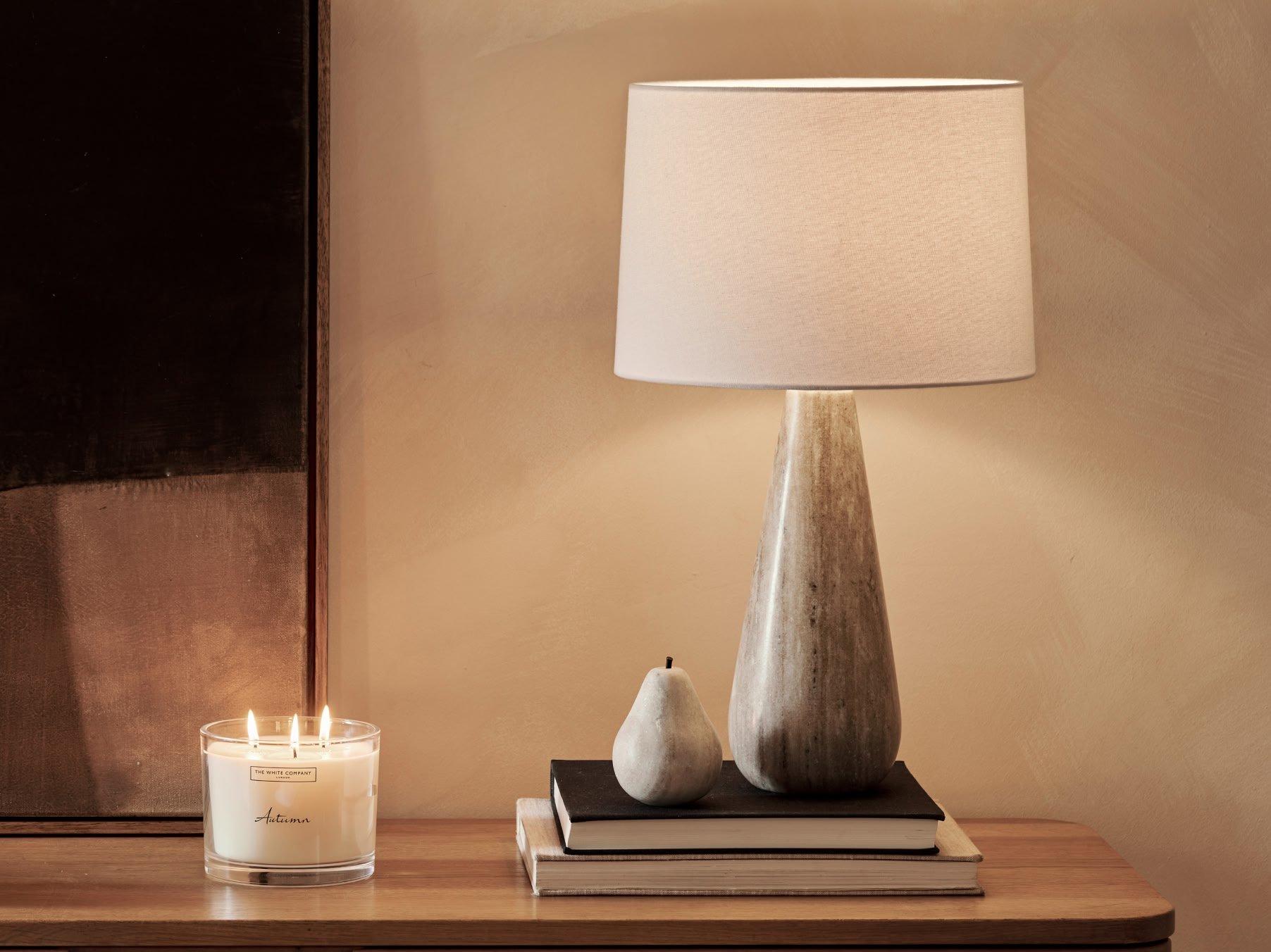 a candle and a book sit on a table next to a lamp