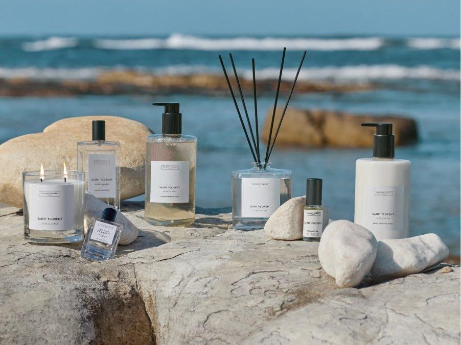 a group of bottles of perfume and candles sit on a rock