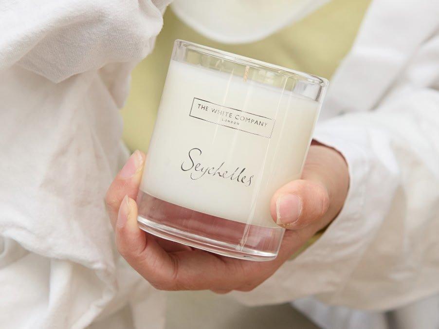 a person holding a candle in a white robe with a white towel