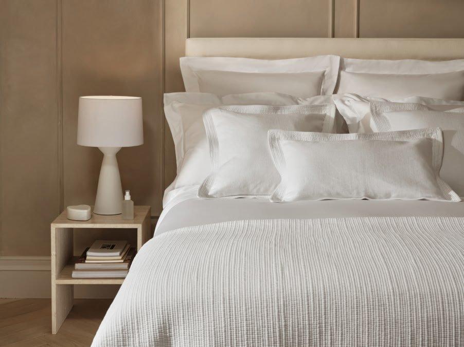 a bed with a white comforter and pillows on it